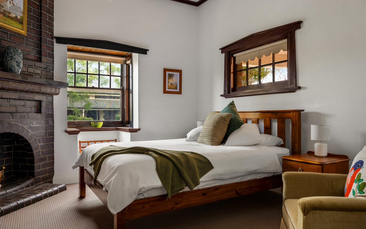 Comfortable heritage bedroom with timber furnishings and original fireplace at Barossa Valley retreat