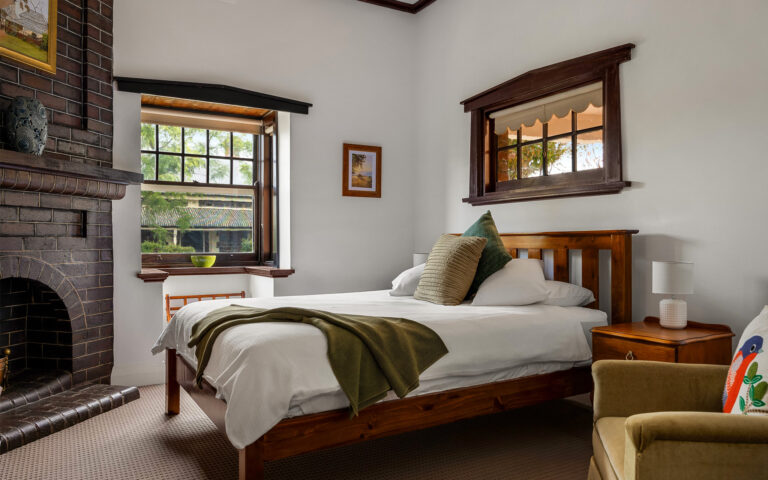 Comfortable heritage bedroom with timber furnishings and original fireplace at Barossa Valley retreat