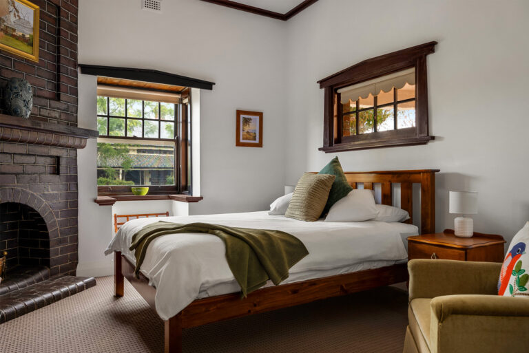 Comfortable heritage bedroom with timber furnishings and original fireplace at Barossa Valley retreat